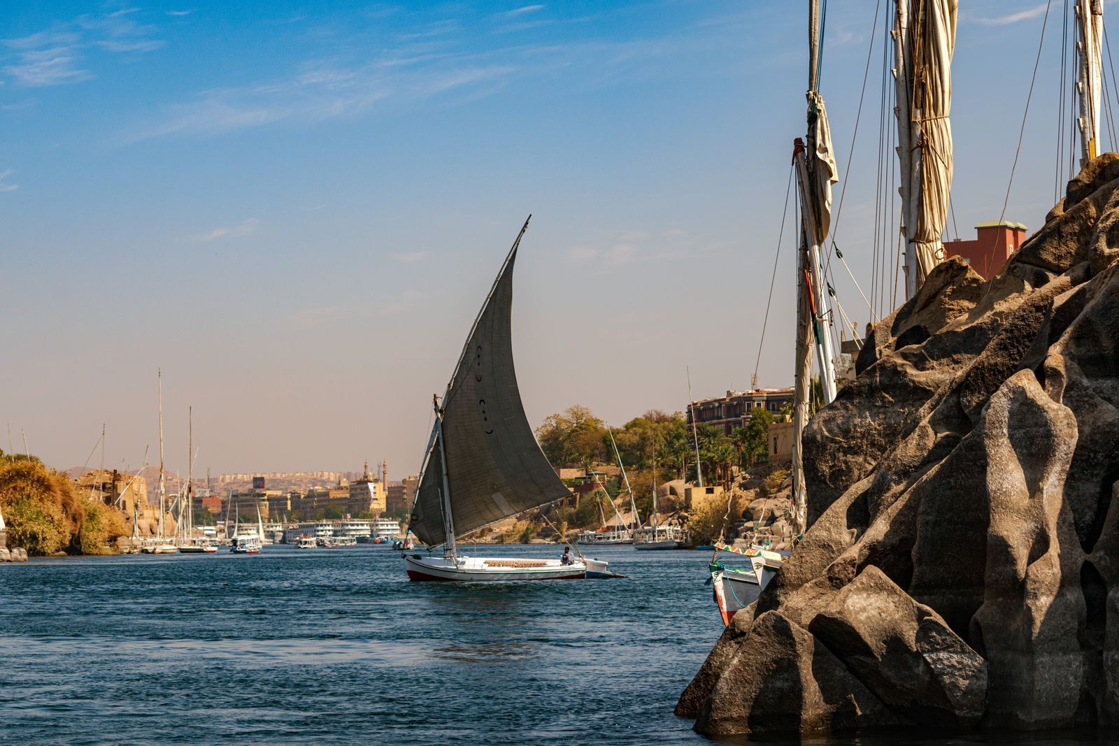 Felucca sailing past granite rocks on the Nile at Aswan, a classic bucket list river cruise scene