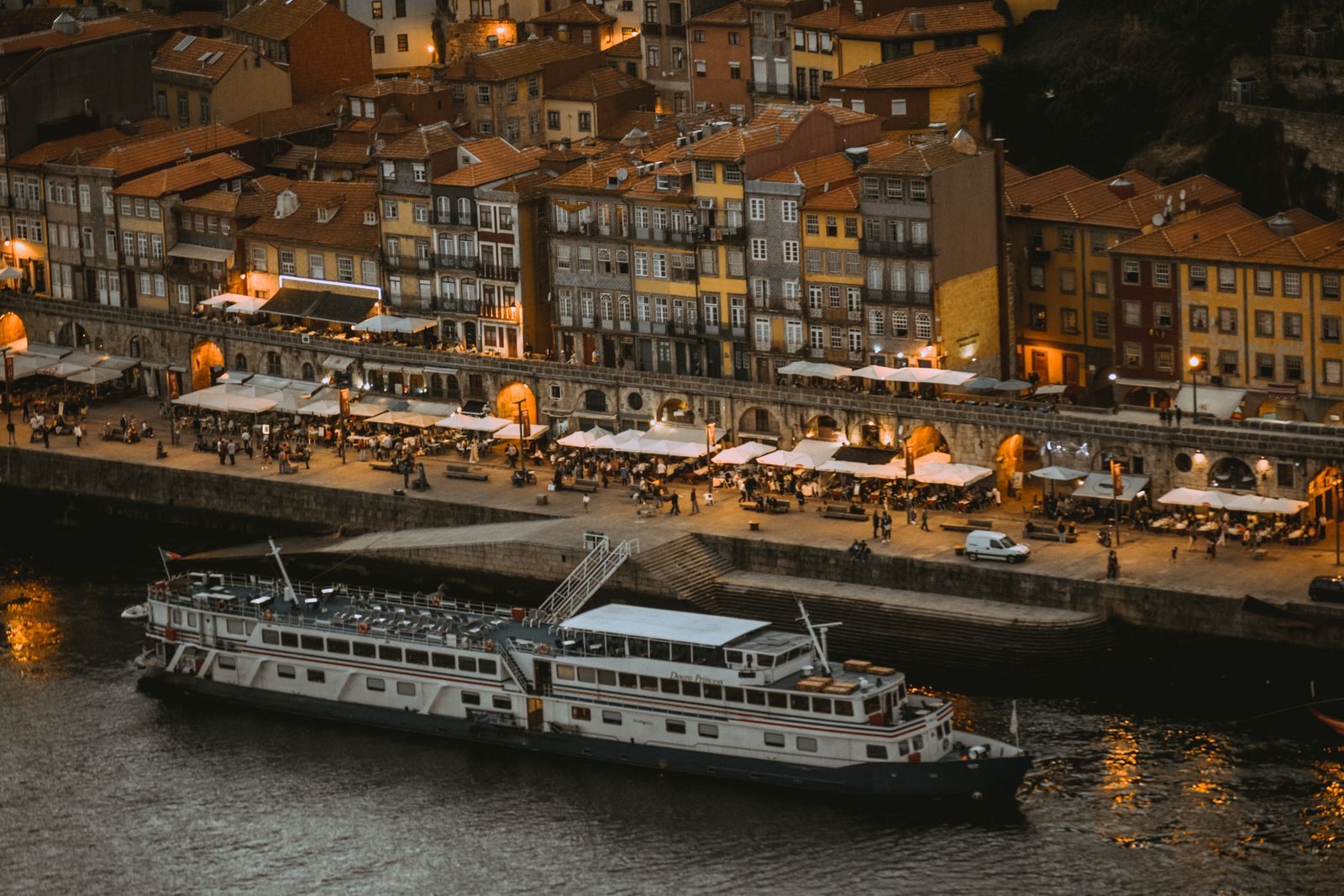 River cruise ship moored on the Douro beside the lit Ribeira waterfront in Porto, Portugal, at night
