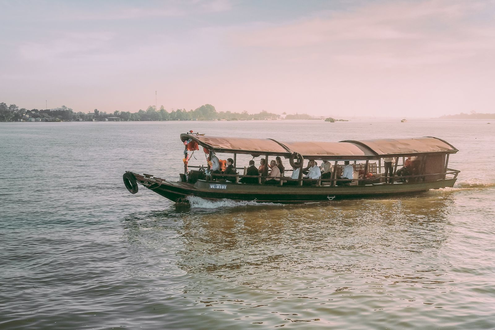 Covered wooden passenger boat on the Mekong at Vinh Long, Vietnam, at dusk
